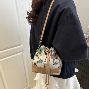 Floral canvas bucket bag with brown leather trim and drawstring for casual crossbody wear