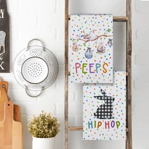 Easter kitchen towels with bunny and bird prints hanging on a rustic wooden ladder