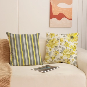 Set of two grey and yellow floral and striped decorative pillows on a beige sofa
