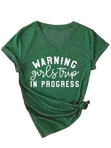 Détail d'un t-shirt col V vert foncé avec imprimé Warning Girls Trip et ourlet noué