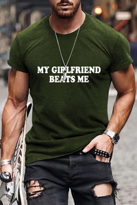 Détail de l'imprimé blanc My Girlfriend Beats Me sur un t-shirt en coton vert foncé