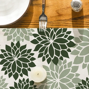 Detail of green floral table runner with woven texture on a wooden dining table