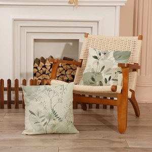Set mit zwei nordischen Kissen mit Blumenmuster auf einem Sessel neben dem Kamin