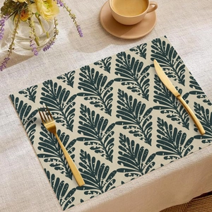 Close-up of bohemian linen placemat with green leaf print next to gold cutlery