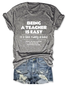 Flat lay detail of grey teacher t-shirt with distressed blue denim shorts on white background