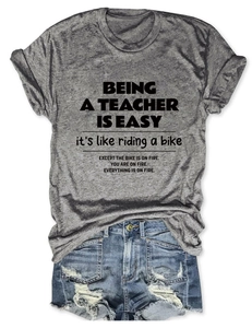 Flat lay of heather grey teacher quote t-shirt with rolled sleeves and denim shorts