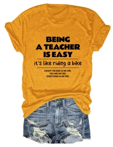 Flat lay of teacher slogan t-shirt in mustard yellow with distressed denim shorts
