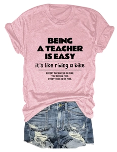 Flat lay of pink teacher slogan T-shirt paired with distressed blue denim shorts