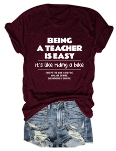 Flat lay of wine red teacher quote T-shirt paired with distressed denim shorts
