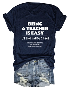 Flat lay of navy blue teacher quote t-shirt paired with ripped denim shorts on white background