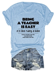 Flat lay of a sky blue teacher slogan cotton T-shirt paired with denim shorts
