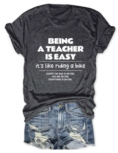 Flat lay of a grey cotton teacher quote t-shirt with blue denim shorts on white background