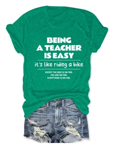 Close-up of green teacher slogan T-shirt paired with distressed blue denim shorts