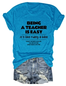 Flat lay of teacher slogan t-shirt in bright blue paired with distressed denim shorts