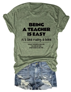 Close-up of olive green teacher-themed t-shirt paired with distressed denim shorts