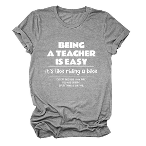 Close-up of Being a Teacher is printed slogan on casual grey cotton t-shirt fabric