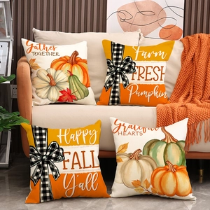 Set of four Thanksgiving pumpkin linen pillow covers on a beige sofa with an orange blanket
