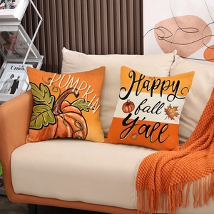 Set of two decorative autumn pumpkin throw pillow covers on a beige sofa with warm orange blanket