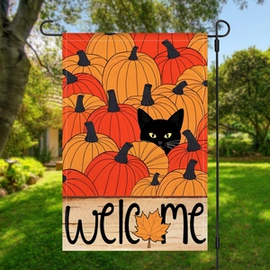 Outdoor garden flag detail with a black cat on pumpkins and a welcome message sign