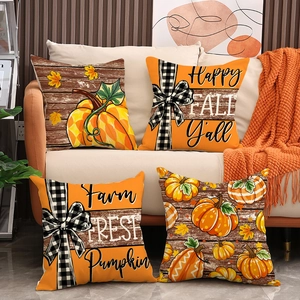 Détail de quatre housses de coussin d'automne à citrouilles sur un canapé beige