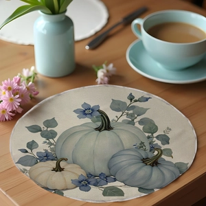 Macro view of round autumn linen placemat with light blue pumpkin and floral patterns