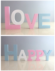 Close-up of matte wood letters spelling LOVE and HAPPY in pastel colors for wall decor