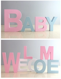 Detailed view of pink and blue decorative wooden letters spelling BABY and WELCOME