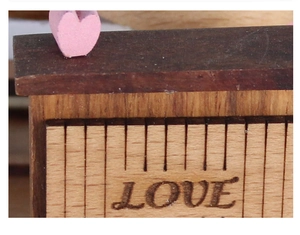 Close-up of wooden music box with LOVE engraving and pink heart decoration