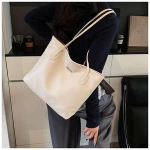Grand sac cabas chic en cuir blanc crème porté par un mannequin dans un intérieur épuré