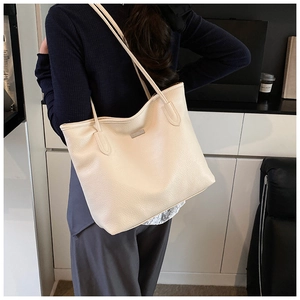 Dettaglio della borsa tote beige con texture litchi di qualità e finiture in metallo