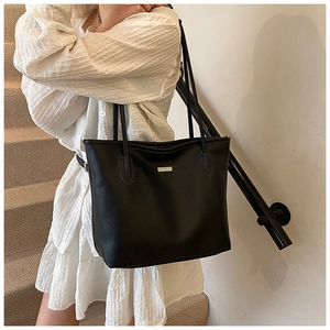 Borsa tote nera con grana litchi indossata da modella con dettaglio logo in metallo