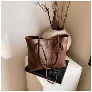 Dettaglio della borsa tote in pelle marrone scuro con elegante targhetta in metallo lucido