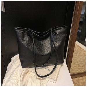 Dettaglio borsa tote in pelle martellata nera con logo metallico e sottili spalline