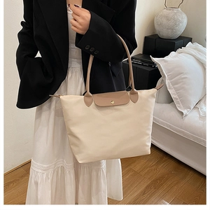 Détail du sac cabas en nylon beige avec poignée en cuir marron et fermeture à bouton-pression