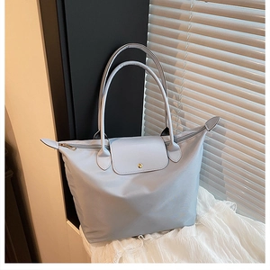 Détail du sac cabas en nylon bleu clair avec anses en cuir et rabat à bouton métallique