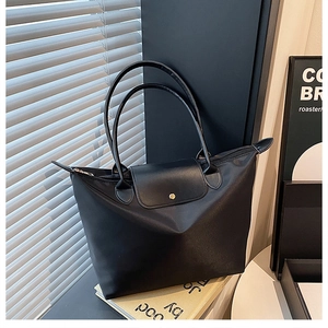 Détail d'un sac cabas en nylon noir avec anses en cuir et fermeture à rabat