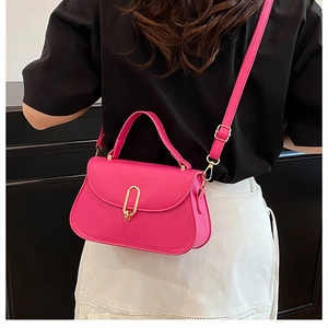 Détail du sac bandoulière magenta avec boucle dorée sur un mannequin en jupe blanche