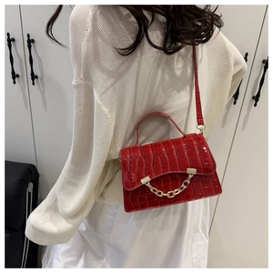 Detail view of a red crocodile pattern box bag with a bold gold chain and shoulder strap