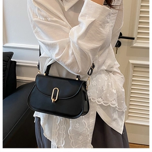 Détail d'un sac à bandoulière noir minimaliste en cuir avec une boucle dorée élégante
