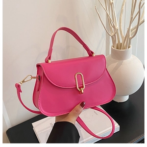 Détail d'un sac à main magenta montrant le cuir texturé et le fermoir doré rotatif