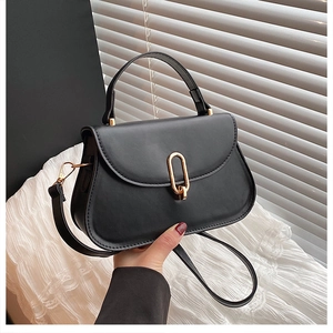 Détail du sac demi-lune noir avec un fermoir métallique ovale doré élégant