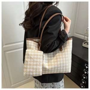 Detail of woven houndstooth tote bag with brown leather handle on model's shoulder