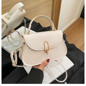 Détail du sac bandoulière blanc crème avec boucle dorée et texture en cuir de qualité