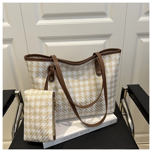 Close-up of woven tote bag set with brown leather handles on a vintage leather chair