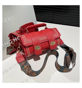 Detail of red leather crossbody bag with vintage ethnic strap and golden turn-lock