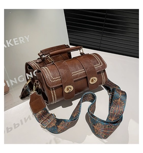 Detail of vintage brown leather boston bag with gold studs and bohemian jacquard strap