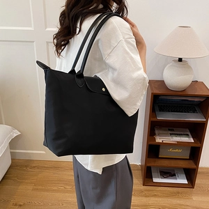 Grand sac cabas noir en nylon avec anses en cuir et bouton pression doré sur l'épaule