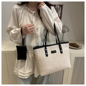 Detail of woven straw tote bag with black leather strap and small matching pouch