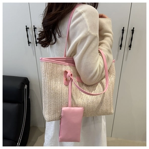 Detail of straw woven tote bag with pink faux leather trim and matching small pouch