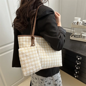 Plaid pattern tote bag with large capacity and brown handles shown on shoulder